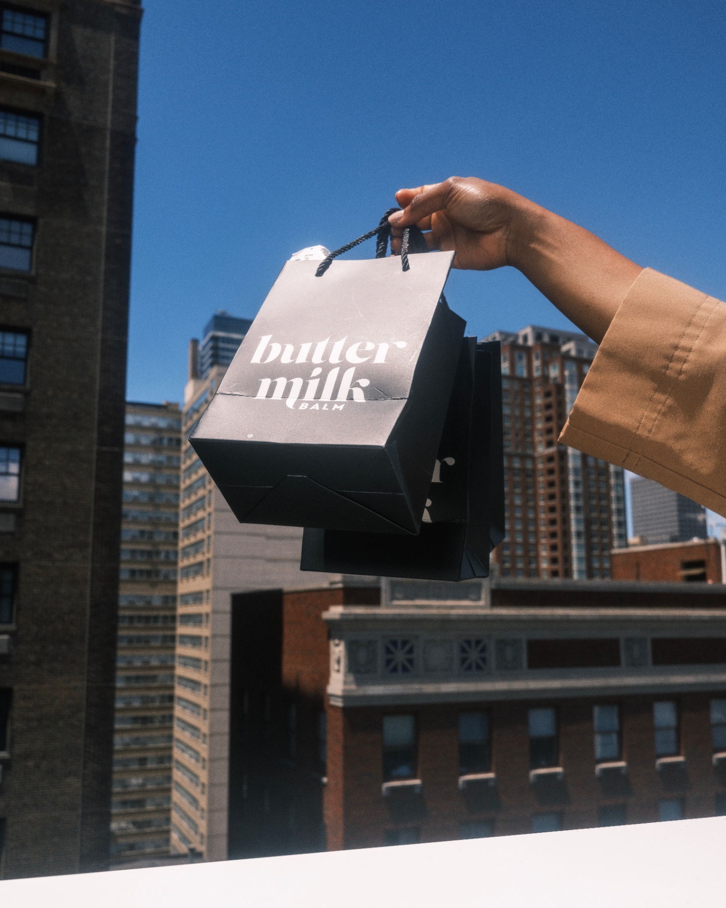 Buttermilk Balm shopping bag against city skyline